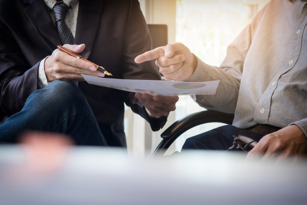 Deux hommes qui échangent sur un document avec des graphiques.